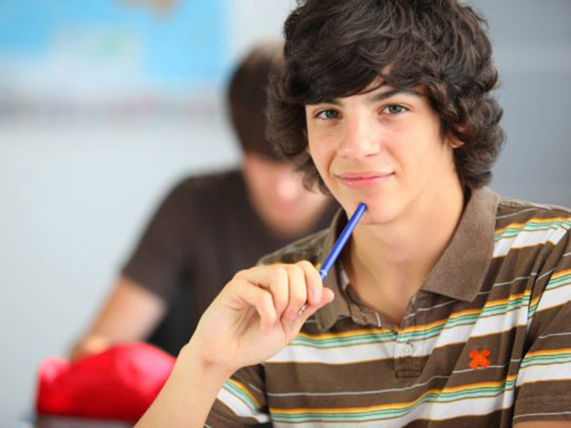 a boy holding a pen and thinking