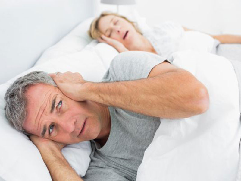 a man covering his hears sleeping next to a woman