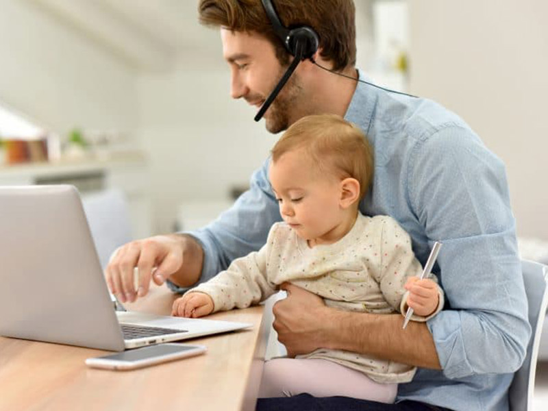 a man sitting with a child working on laptop